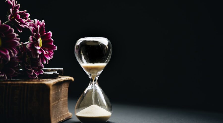 clear hour glass beside pink flowers