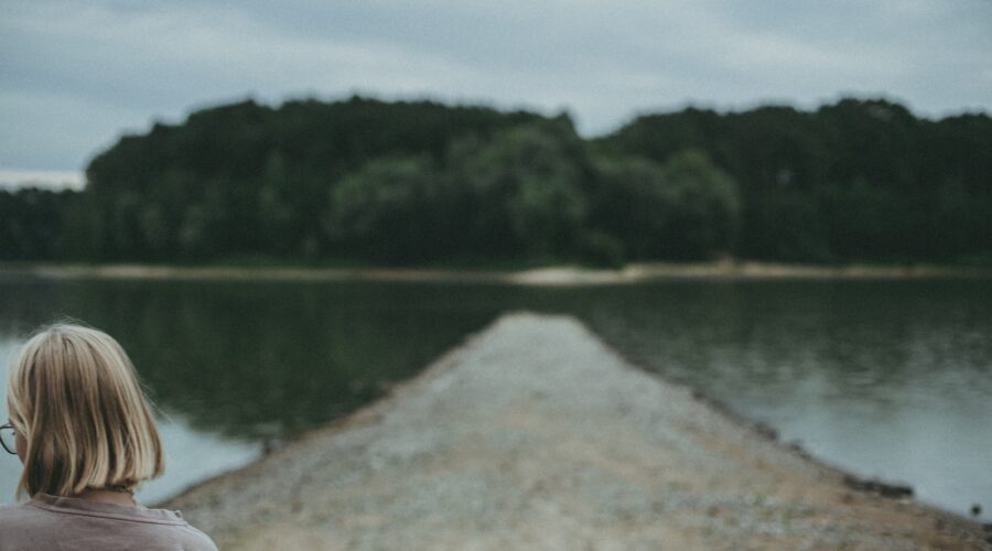 woman in dirt road between ocean