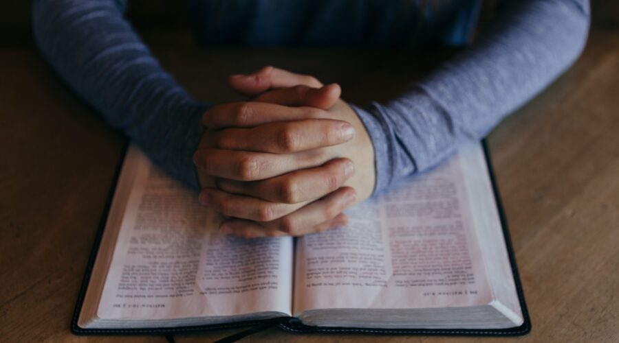 man holding his hands on open book