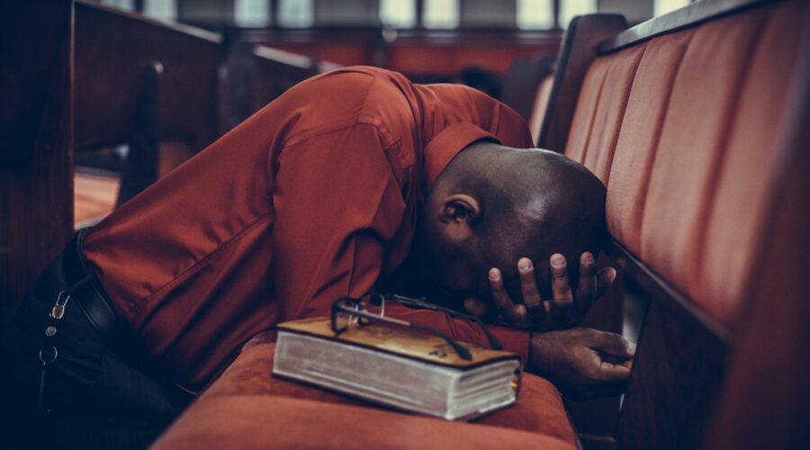 man in orange top beside eyeglasses on brown book