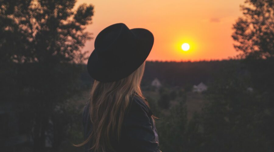 woman wearing black hat staring at sunset