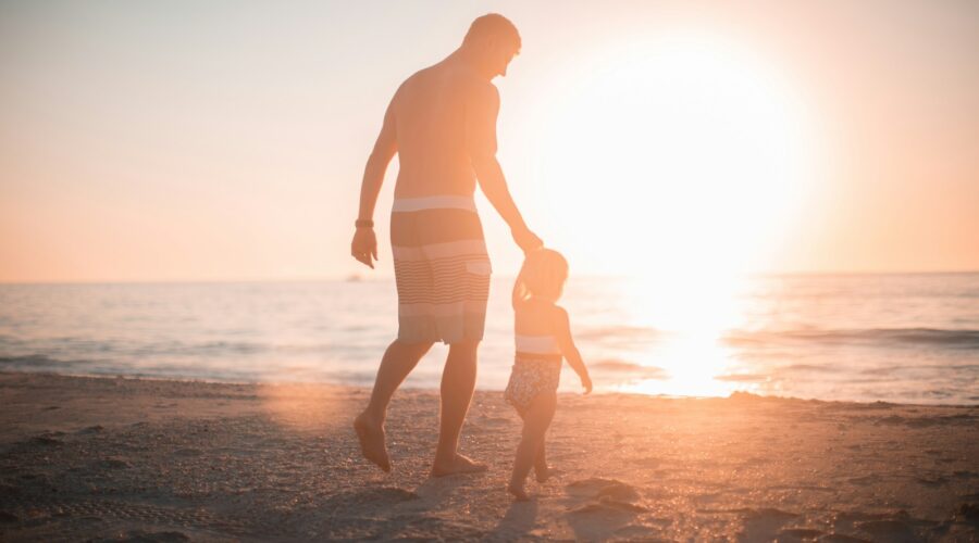 man holding girl heading towards sea