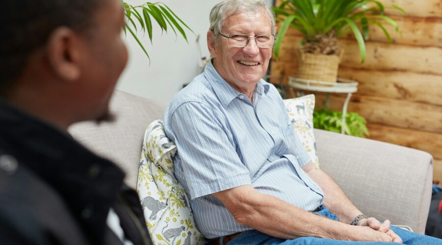 a man sitting on a couch talking to another man