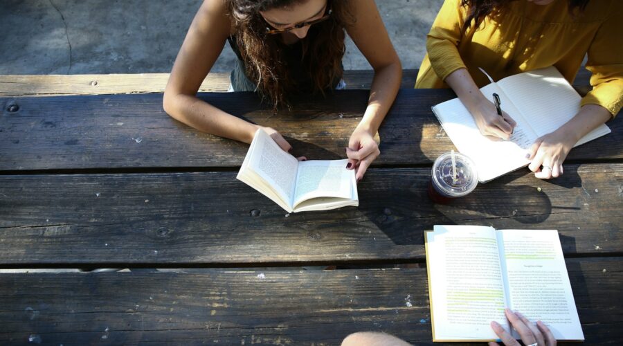 woman reading book while sitting on chair