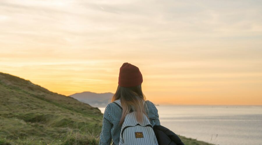 woman standing on cliff carrying backpack