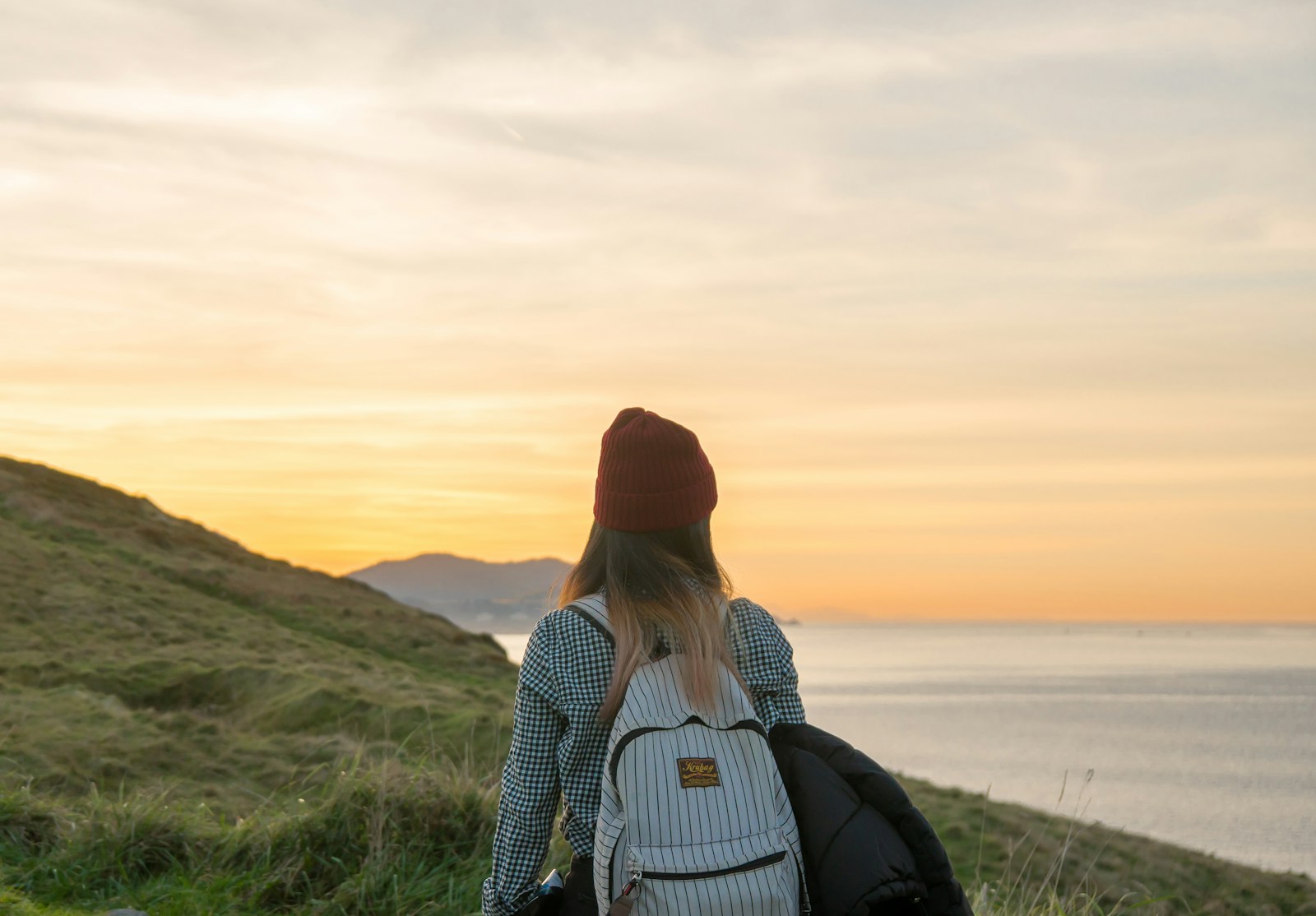 woman standing on cliff carrying backpack