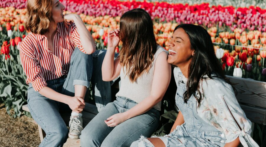 three women sitting wooden bench by the tulip flower field