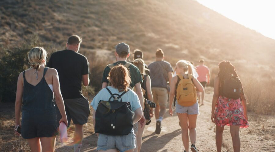 people walking on dirt road near mountain during daytime