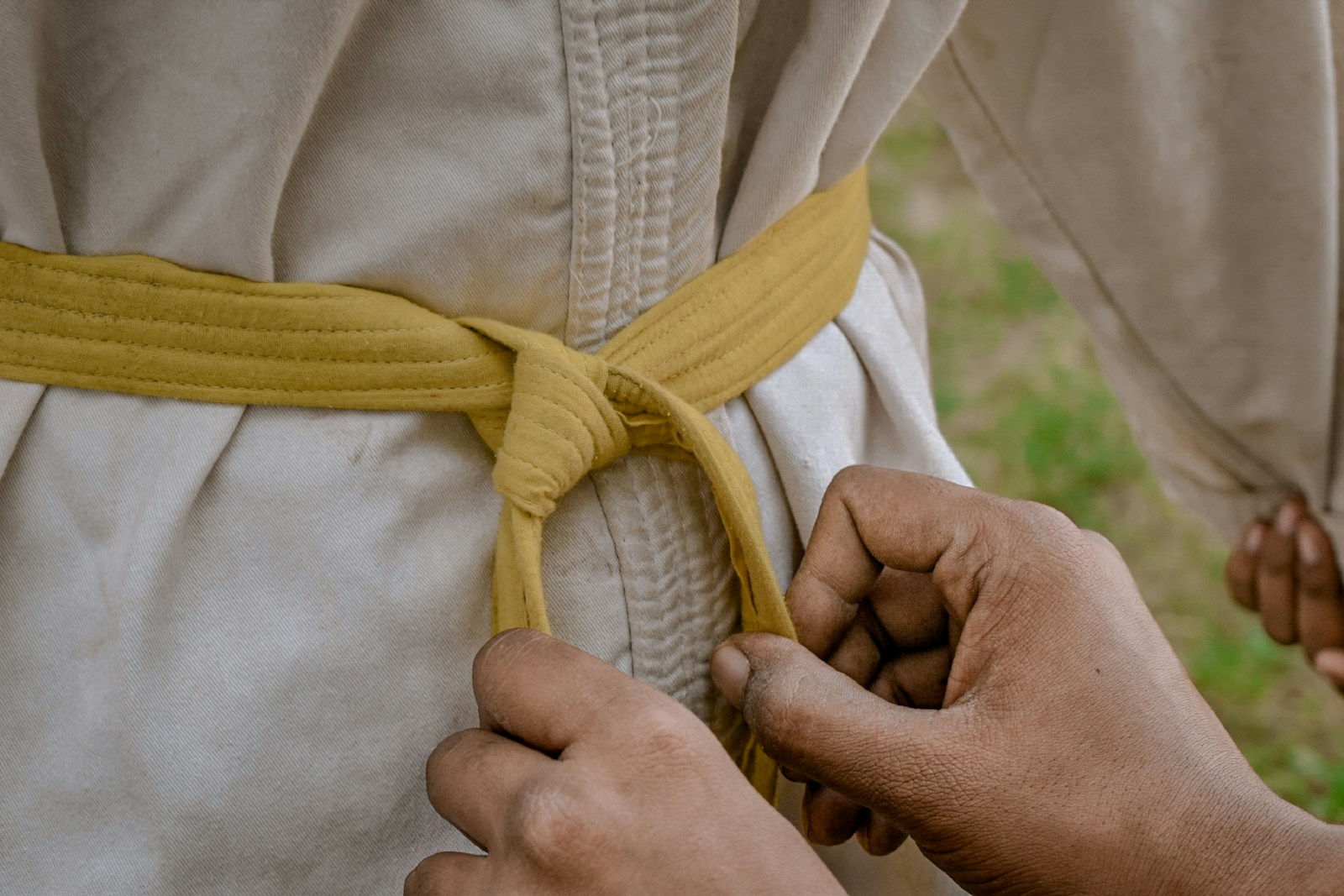 a person tying a belt around another person's waist