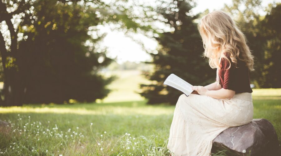 woman sitting while reading book