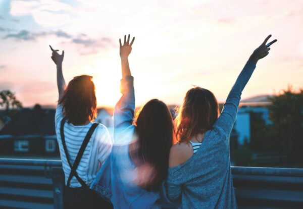 photo of three women lifting there hands