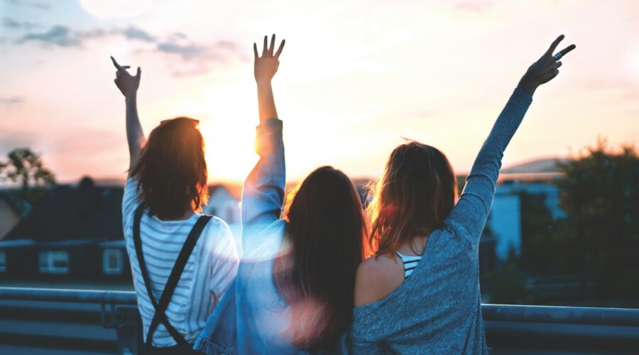 photo of three women lifting there hands