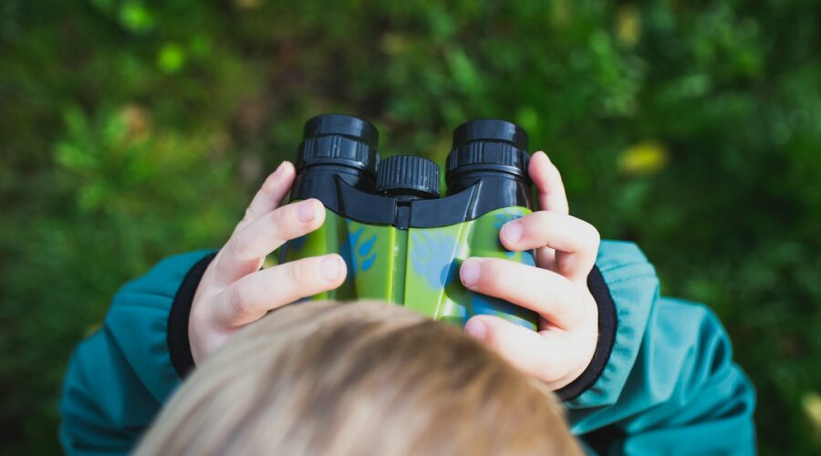 boy in green shirt holding binoculars