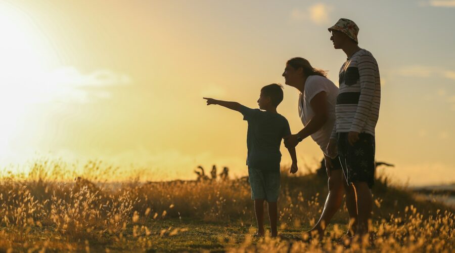 man and woman holding hands while walking on grass field during sunset